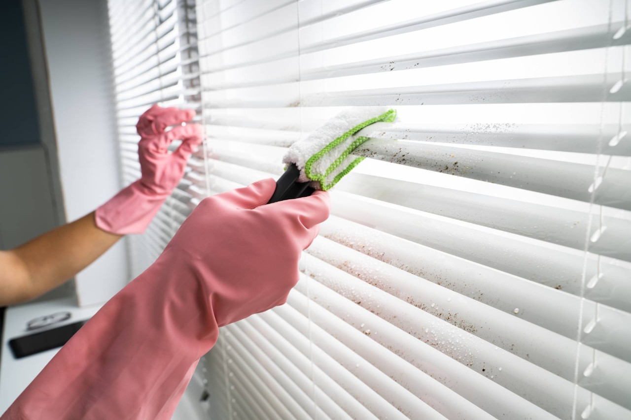 A person wearing pink rubber gloves performing blind cleaning with a duster tool at Eagle Harbor Window Coverings near Bainbridge Island, WA 