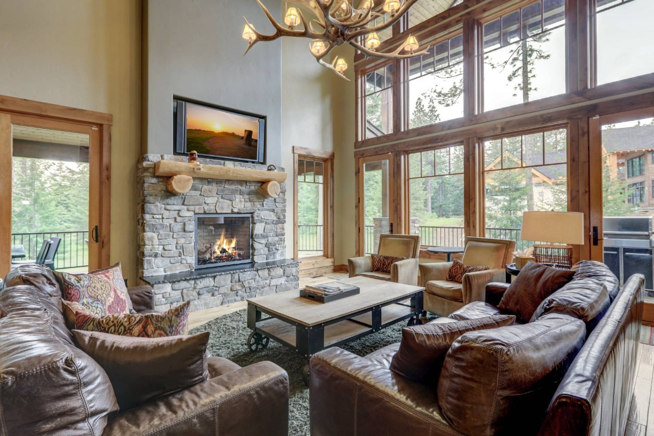 Living room with a rustic interior design, featuring an antler chandelier and several windows without window treatments nearBainbridge Island, WA